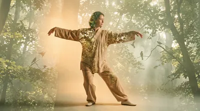 Double exposure of a practitioner in crane stance blended with sage green forest and bird silhouettes