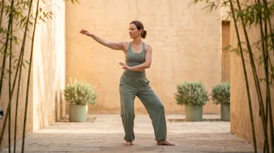 Woman in sage green performing tai chi single whip in a minimalist courtyard at dawn