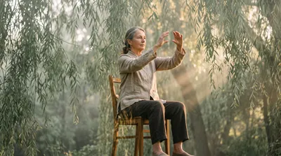 Double exposure of an older person doing seated qigong blended with sage green willow branches