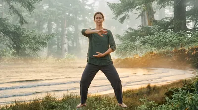 Double exposure of a practitioner performing shibashi wave hands blended with sage green ocean waves