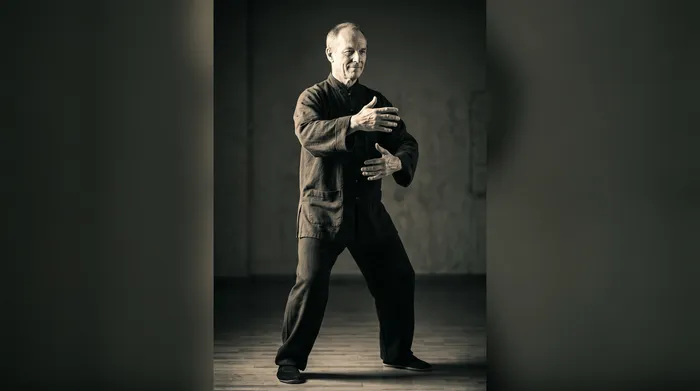 Practitioner performing the Sun style open-close hands movement with a high, upright stance
